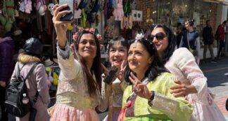 A group of happy women travelers posing in colorful traditional Korean Hanboks at Gyeongbokgung Palace, Seoul, during a Jugni women-only group tour to South Korea.