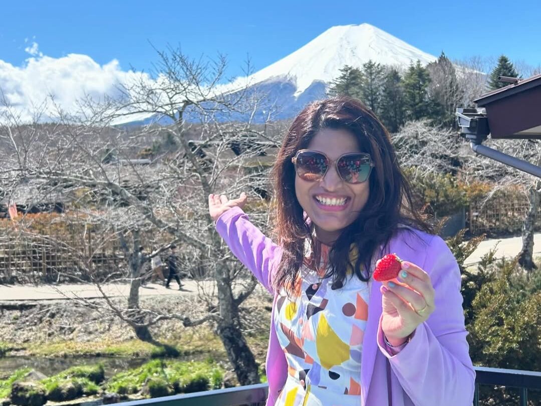 A solo woman traveler posing happily in front of Mount Fuji during a women-only group trip to Japan