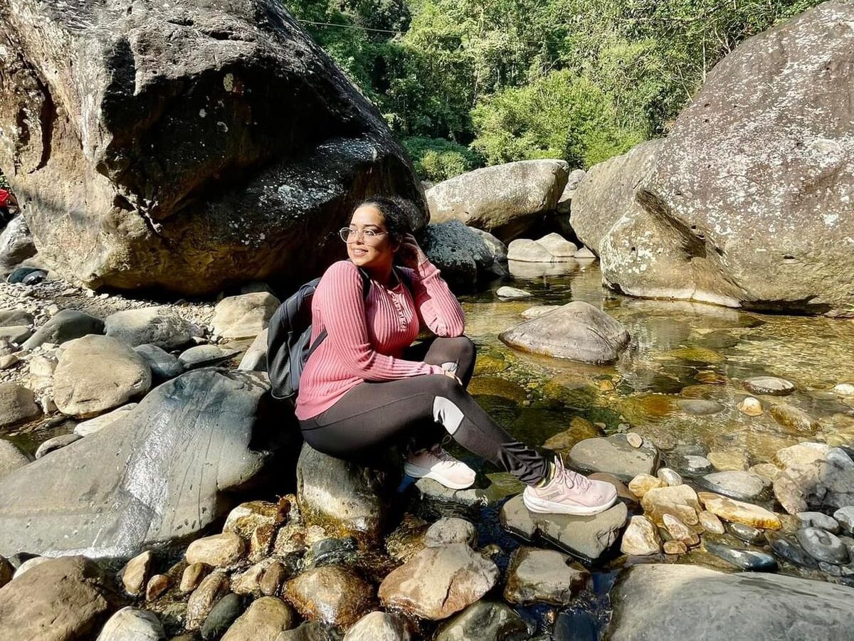 Female traveler relaxing by a mountain stream during a scenic women’s hiking trip in Meghalaya