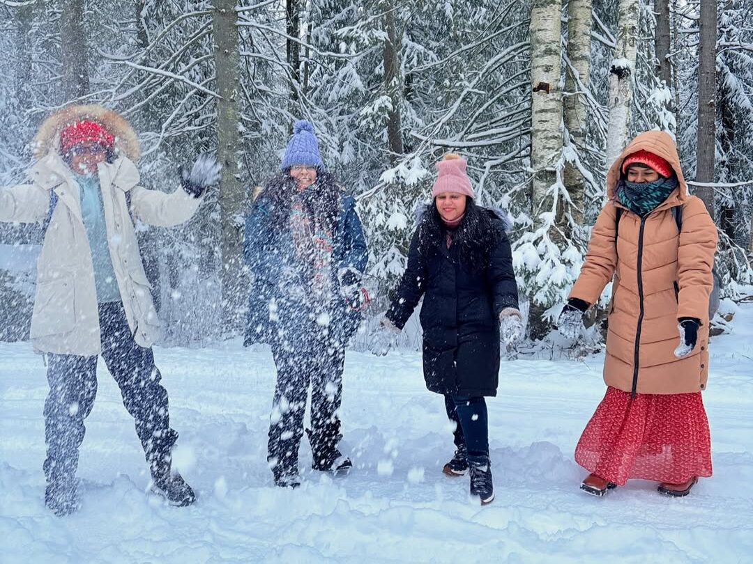 Women enjoying snow play in Finnish forest during exclusive women-only Arctic adventure
