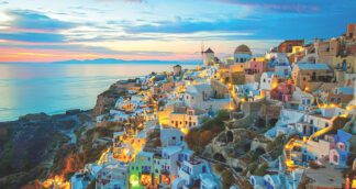 Golden hour in Santorini during Jugni’s Greece group tour for solo women – soft light over blue domes and whitewashed houses.