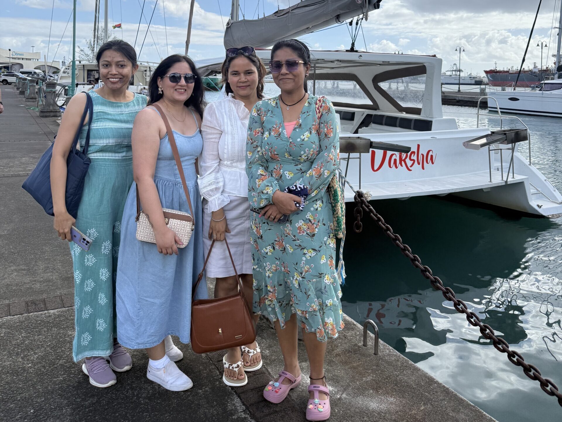 Four women pose in front of a boat in Mauritius on an all-women group trip.