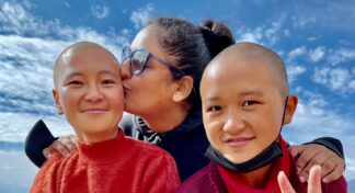 Women traveller sharing a heartwarming moment with young monks during Jugni Travel's Ladakh women-only group trip
